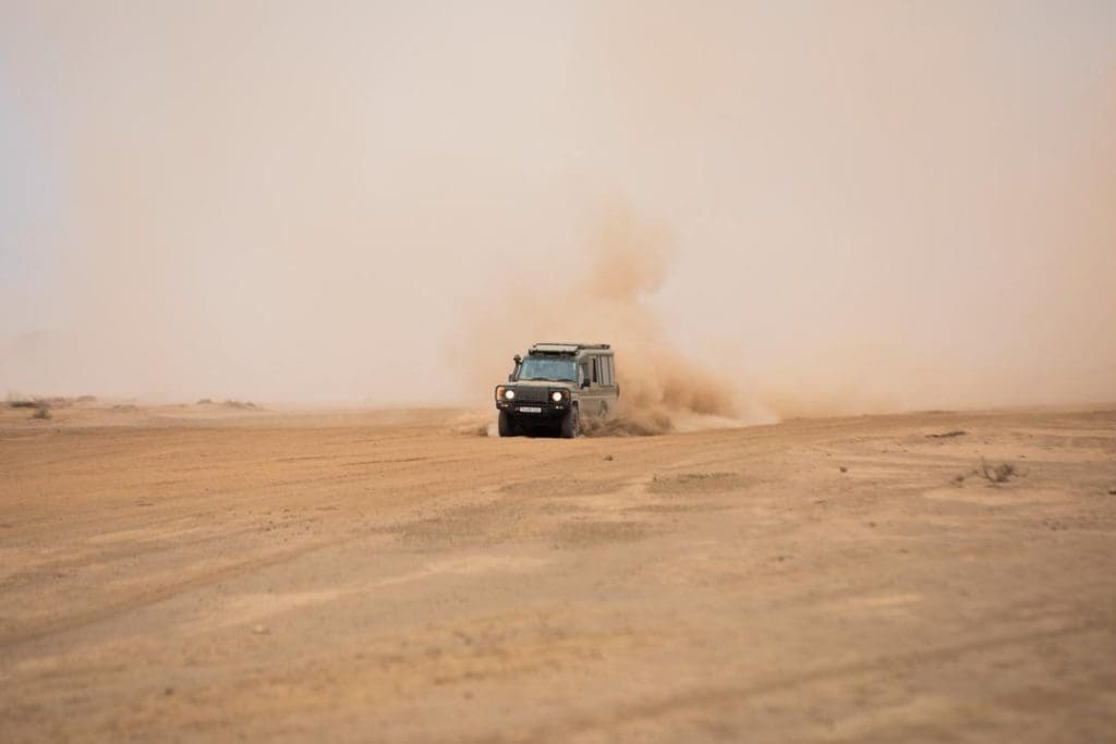 4x4 safari vehicle driving across the dusty plains of Tanzania during a game drive.